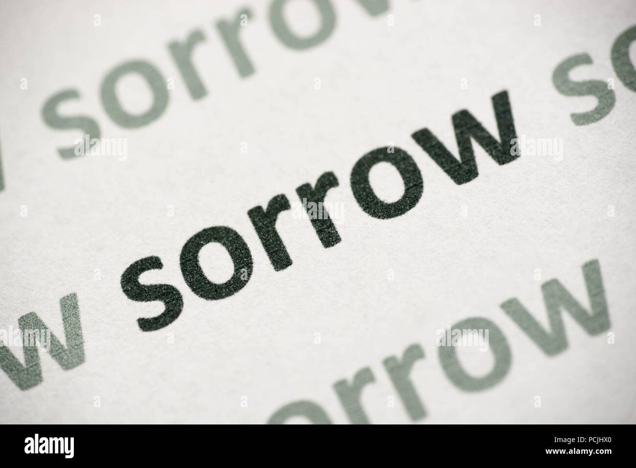 word sorrow printed on white paper macro Stock Photo
