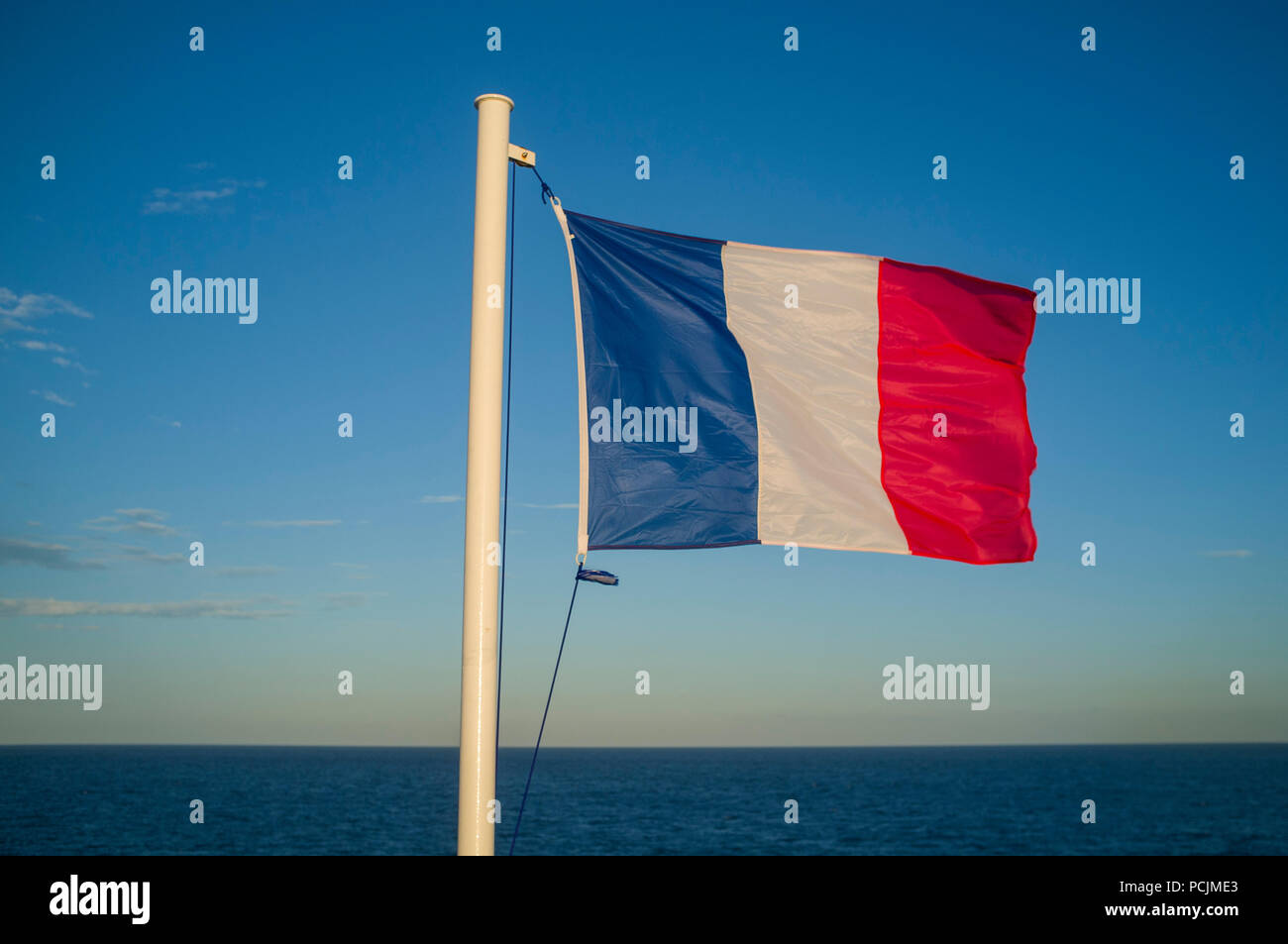 The French Tricolour or Tricolore flag flies in the evening sun on the cross-channel ferry from Le Havre. Stock Photo