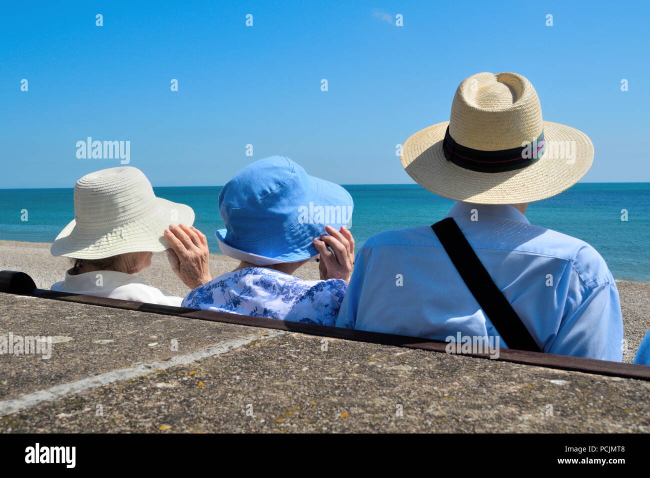 People wearing summer hats on a windy summer day on the beach Stock Photo