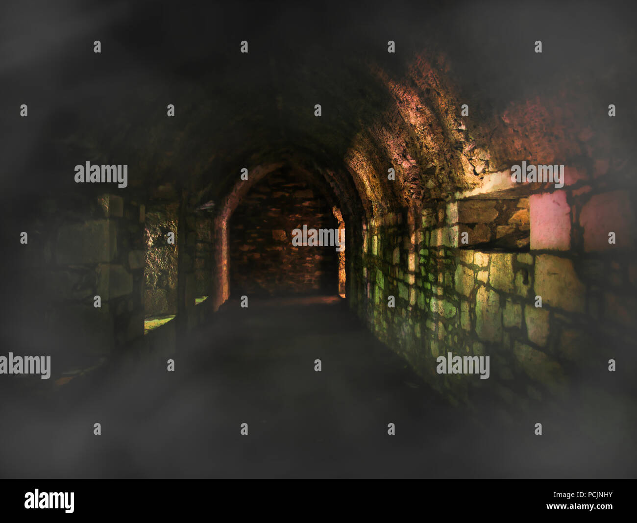 Underground tunnel or cellar with fog and colorful light effects on the individual stones from the brickwork Stock Photo