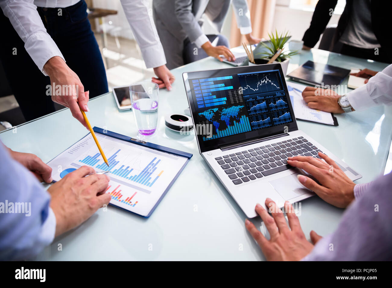 Businesspeople Using Laptop While Analyzing Graphs At Meeting Stock Photo