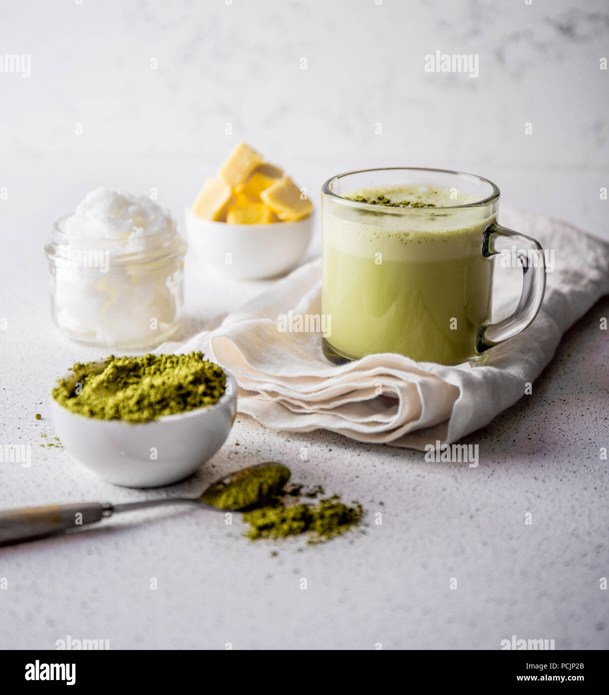 BULLETPROOF MATCHA. Ketogenic keto diet hot drink. Tea matcha blended with coconut oil and butter. Cup of bulletproof matcha and ingredients on white background Stock Photo