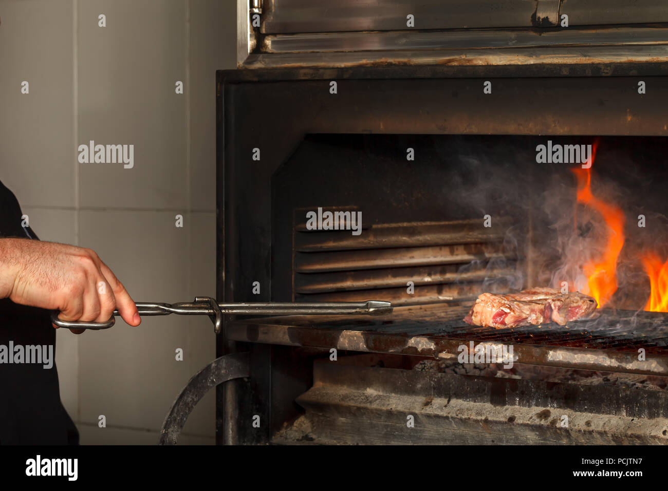 A Cook Fries Meat On An Open Fire In A Large Kitchen Stove Stock