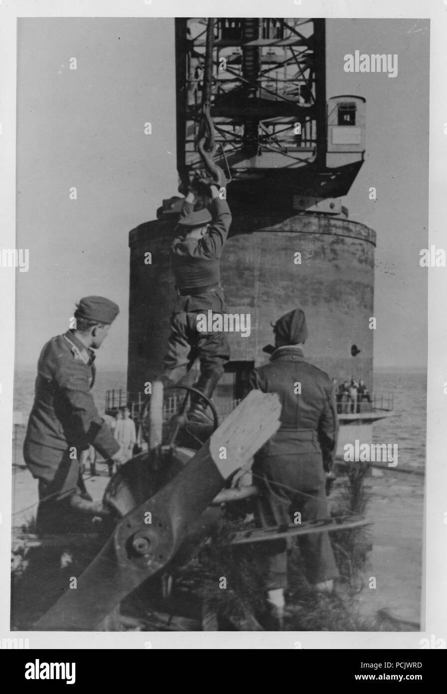 Image from the photo album of Oberleutnant Wilhelm Gaul - An officer of 2. Staffel, Küstenfliegergruppe 906 is hoisted by the crane used to lift the unit's Heinkel He 115 floatplanes into the water, at Brest in 1941 or 1942. Stock Photo