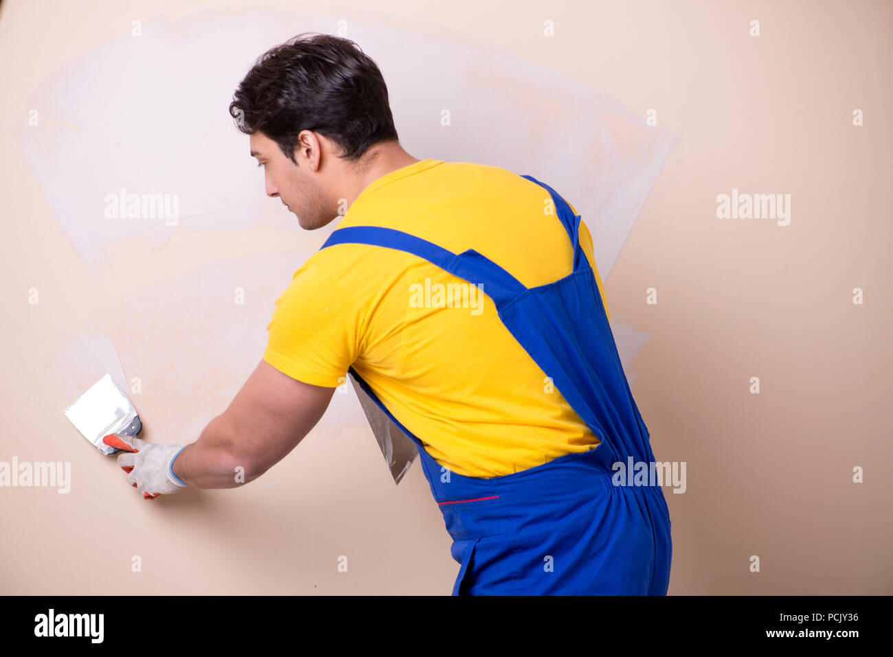 Young contractor employee applying plaster on wall Stock Photo