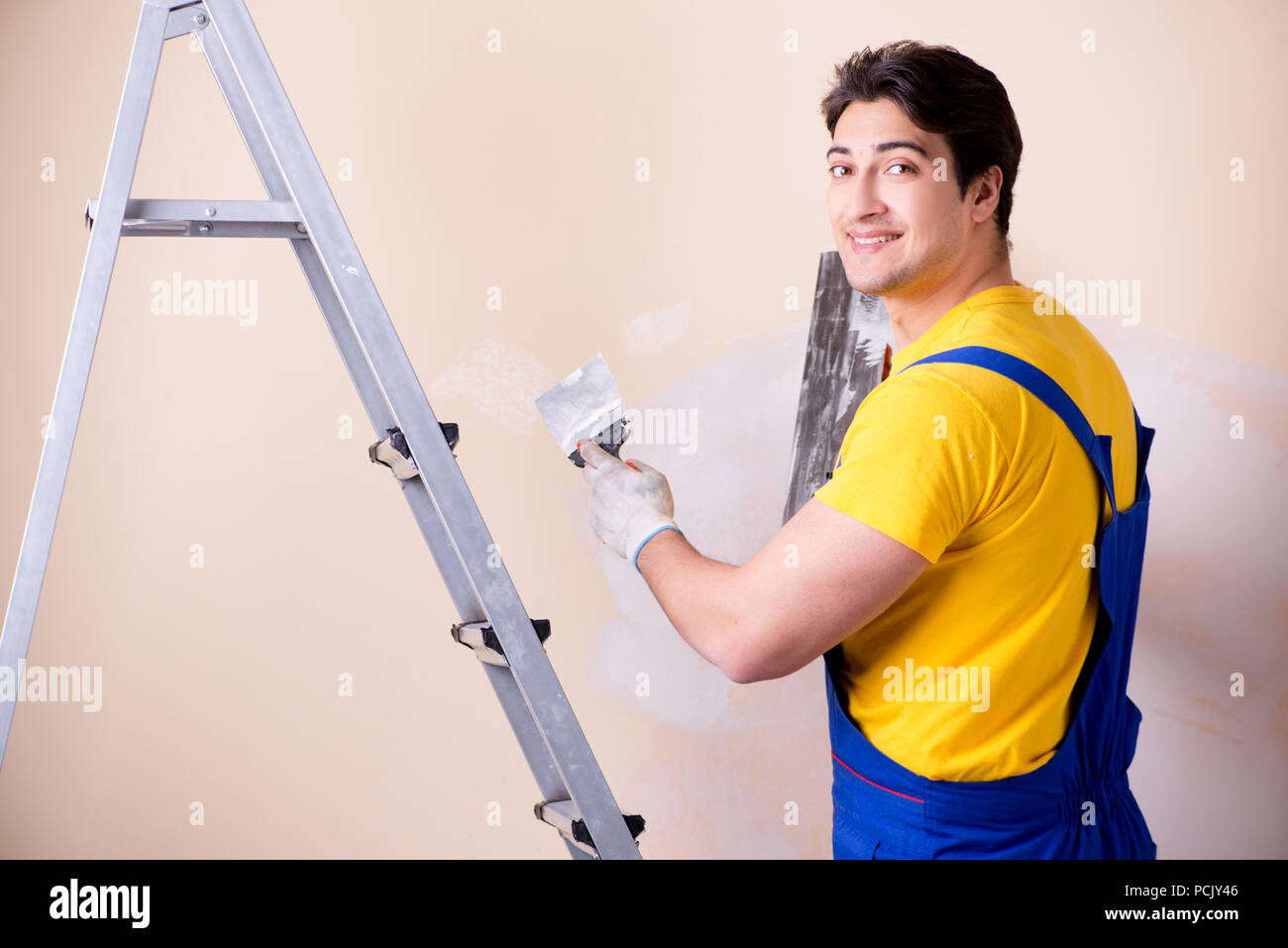 Young contractor employee applying plaster on wall Stock Photo