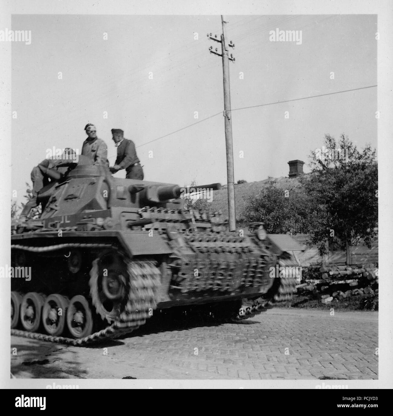 Image from a photo album relating to II. Gruppe, Jagdgeschwader 3: A Panzer III of 13th Panzer Division rolls down a Russian road in summer 1941. The crew has fixed spare tracks to the front of the tank for added protection against Soviet anti-tank weapons. Stock Photo