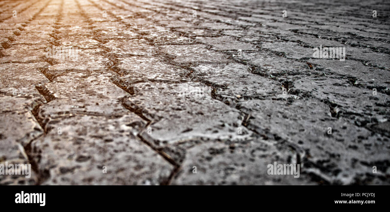 Old paved cobblestone road close-up on a sunset background. Stock Photo