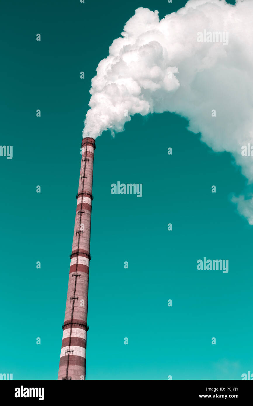 The thick smoke rises high from the industrial pipes. Pollution of the environment with waste products. Stock Photo