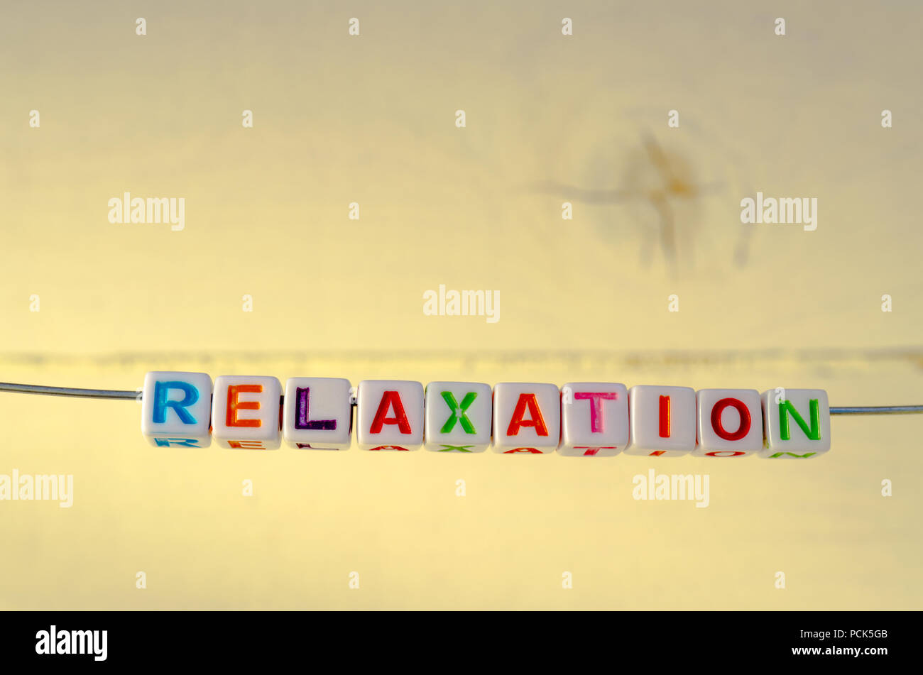 A Studio Photograph of Alphabetical Beads Suspended on a Wire Spelling 'Relaxation' Stock Photo