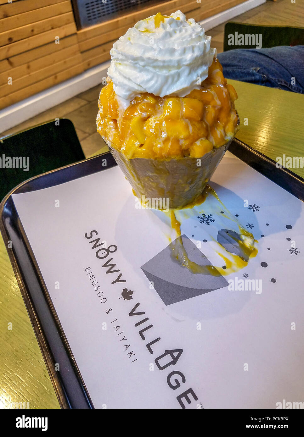 Mango shave ice also called bingsoo at Korean shave ice shop in Richmond, BC, Canada. Sweet condensed milk is added to shaved ice and topped with fruit and whipped cream. Stock Photo