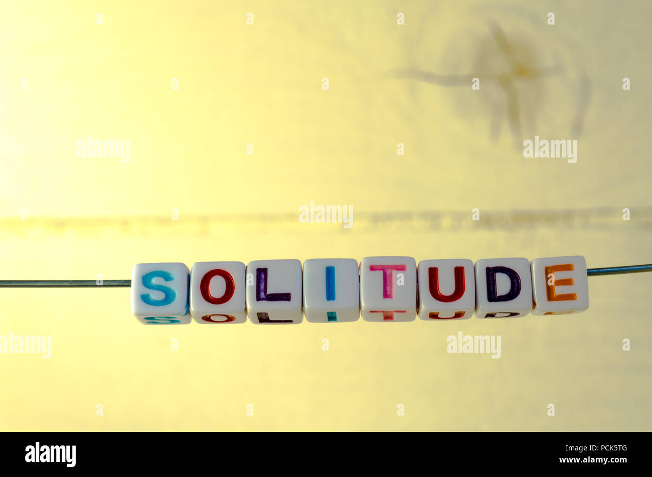A Studio Photograph of Alphabetical Beads Suspended on a Wire Spelling 'Solitude' Stock Photo