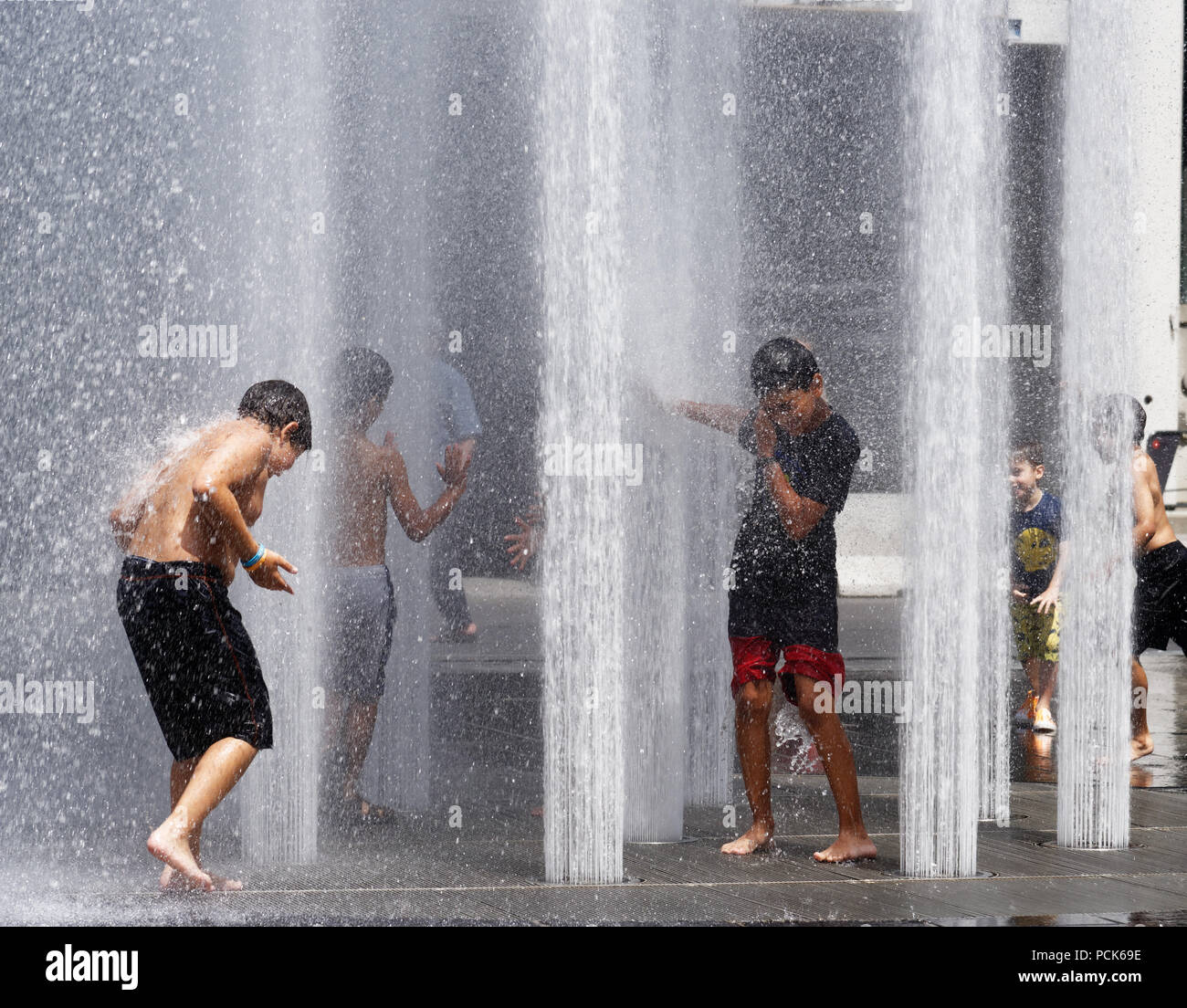 Children cooling off playing in water fountains in on Rue Jeanne Mance in Montreals Entertainment District. Taken during the 2108 heatwave. Stock Photo