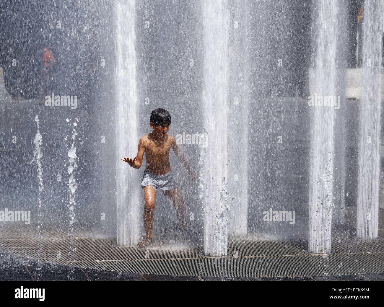 Children cooling off playing in water fountains in on Rue Jeanne Mance in Montreals Entertainment District. Taken during the 2108 heatwave. Stock Photo