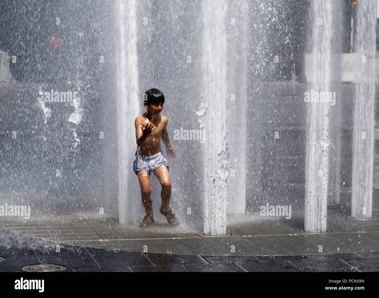 Children cooling off playing in water fountains in on Rue Jeanne Mance in Montreals Entertainment District. Taken during the 2108 heatwave. Stock Photo