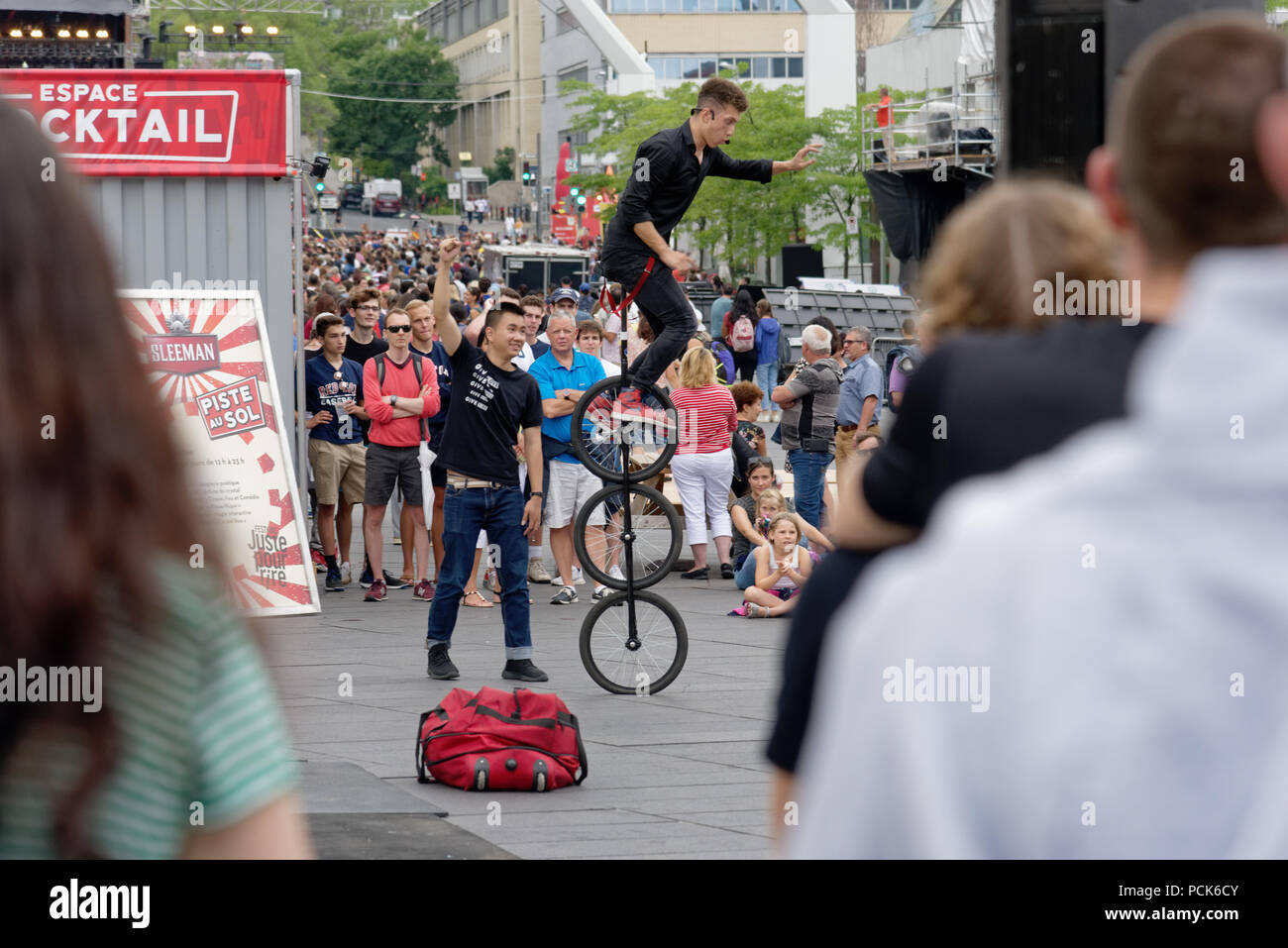 Crowds gather to watch a three wheel unicycle at the Just For Laughs festival in Montreal Stock Photo