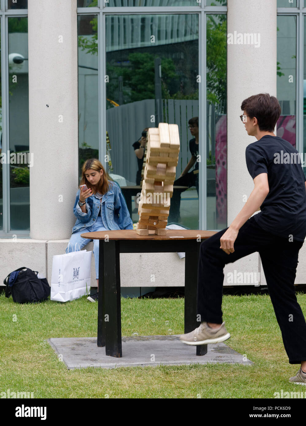 A a teenage boy playing giant Jenga, and watching his tower fall,  outside at the Jeux Loto Quebec games festival in Montreal Stock Photo