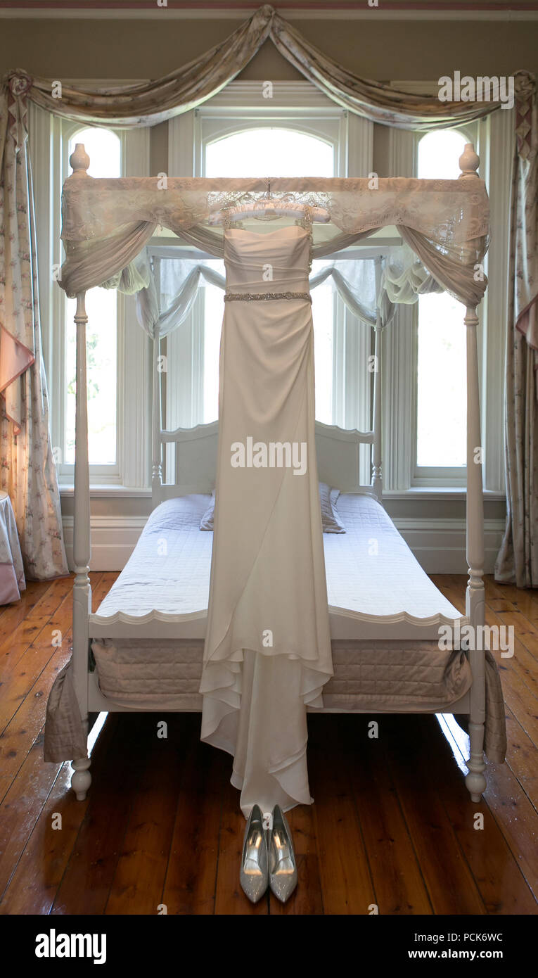 Wedding dress hung up on four poster bed prior to the wedding. Stock Photo