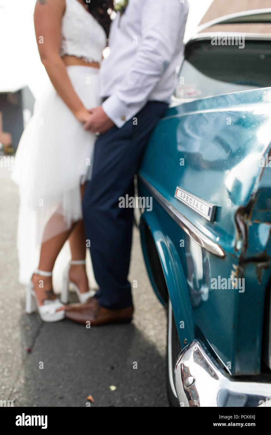 Bride and groom leaning against their wedding car Stock Photo - Alamy