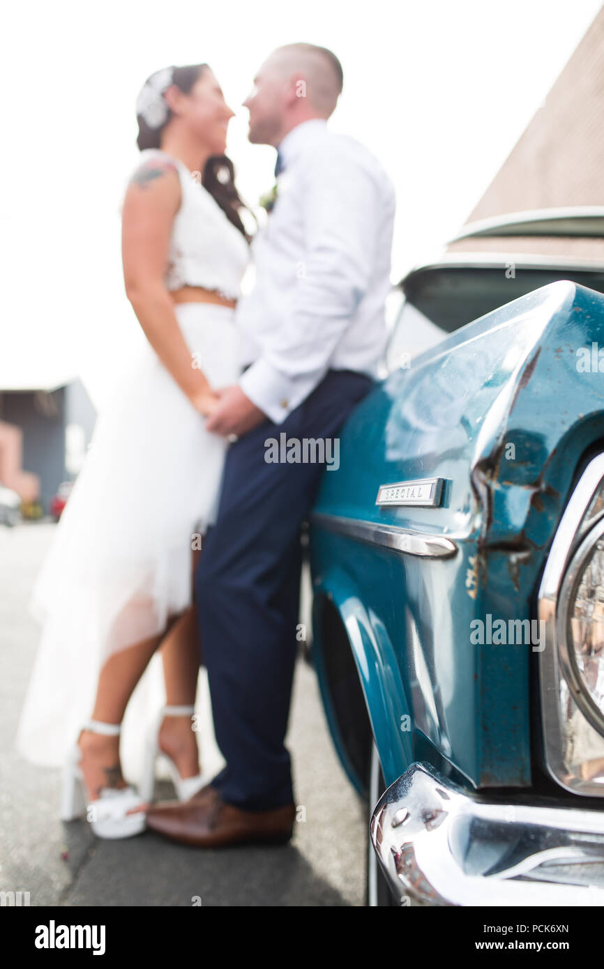 Bride and groom leaning against their wedding car Stock Photo - Alamy
