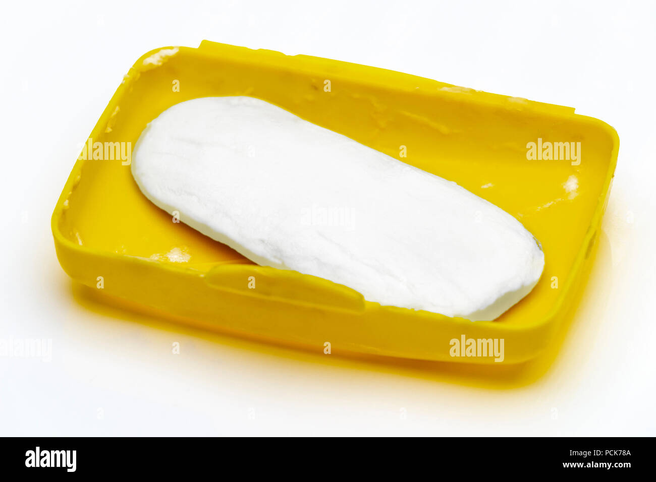 Soap residue in a yellow plastic soap dish on a white background Stock