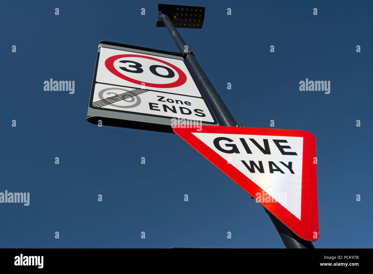 british road signs indicating give way and the start of a 30mph speed limit and the end of a 20mph speed limit zone Stock Photo