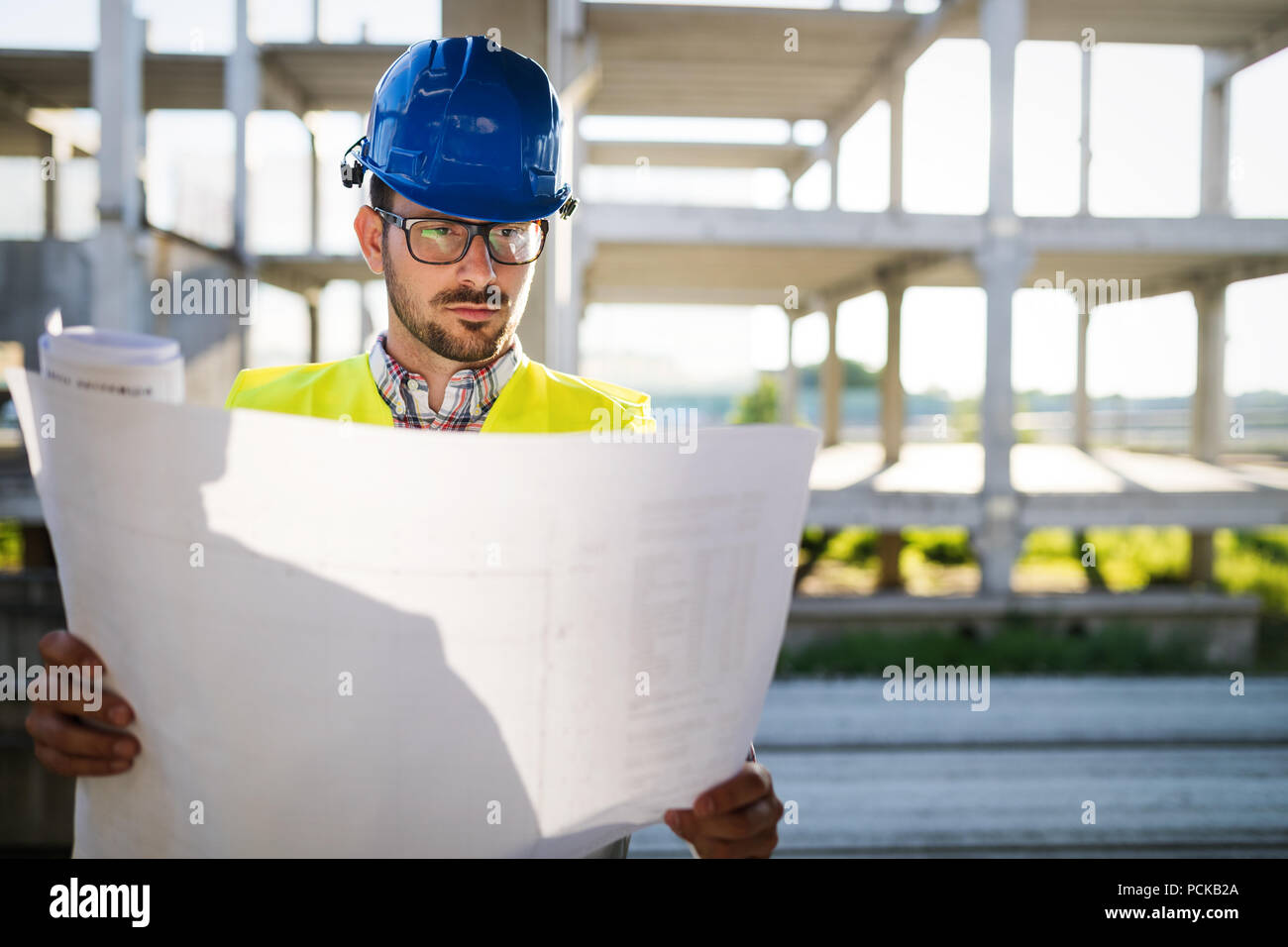 Construction engineer in hardhat with project in hands Stock Photo