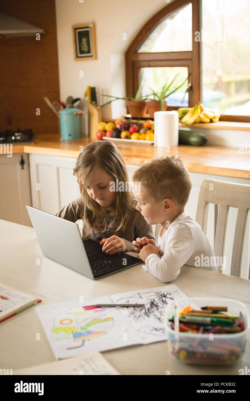 Children using laptop together in kitchen Stock Photo
