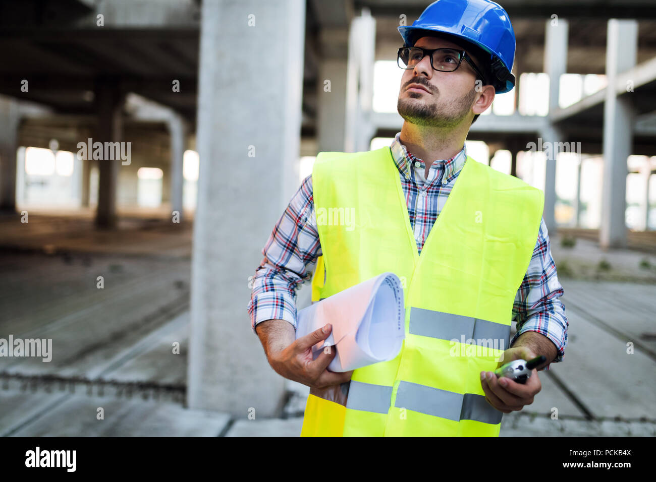 Engineer working on construction site and holding blueprint Stock Photo ...