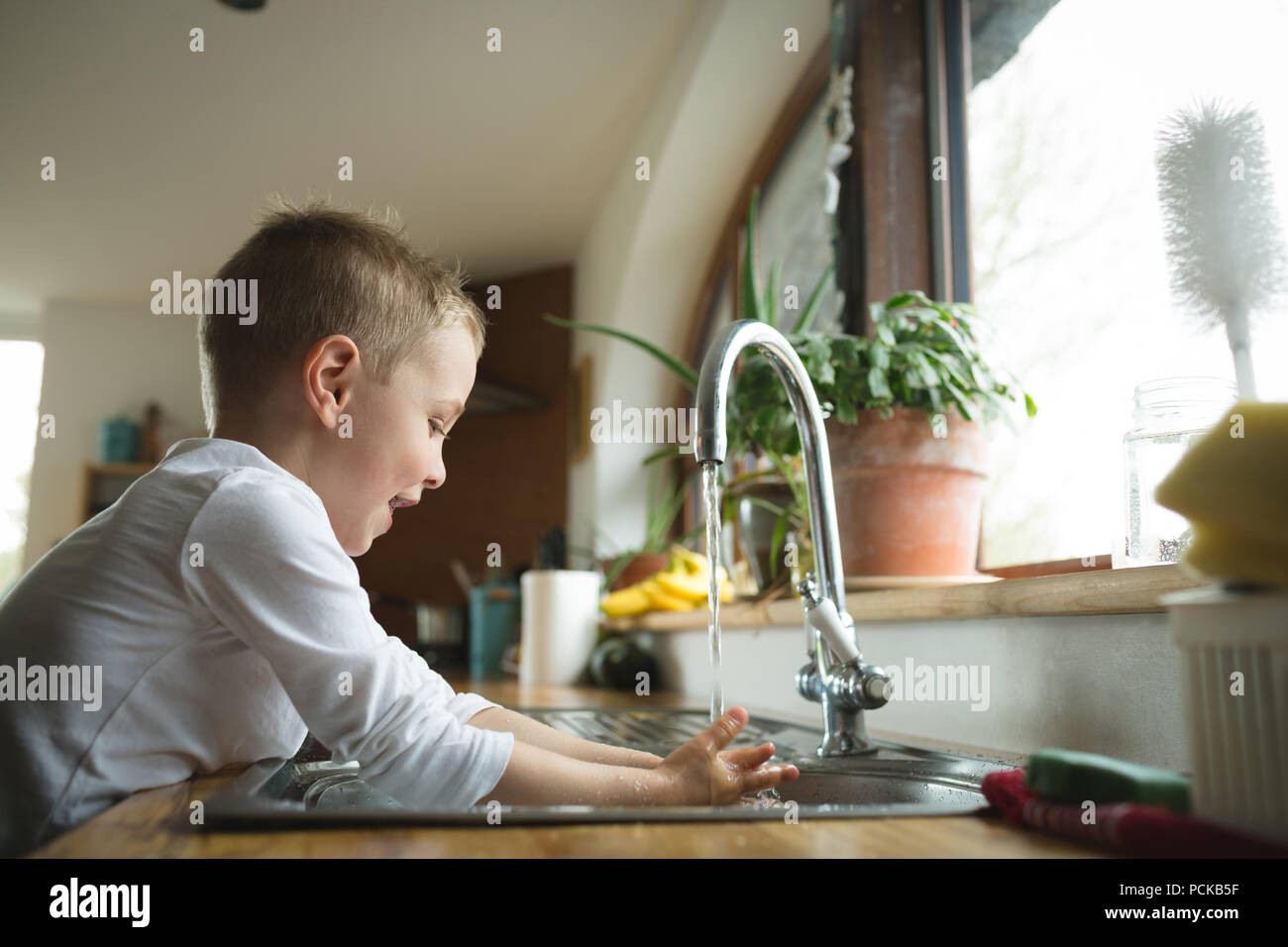 Boy washing hands on kitchen sink Stock Photo