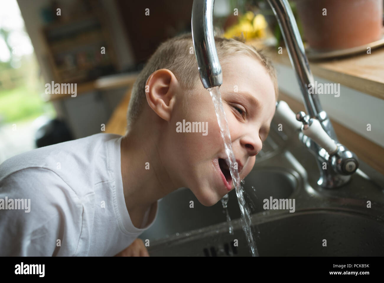 Young boy drinking water from tap in kitchen at home Stock Photo - Alamy