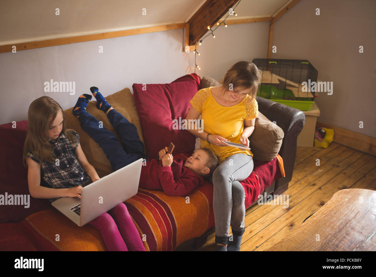 Family on sofa using multimedia devices Stock Photo