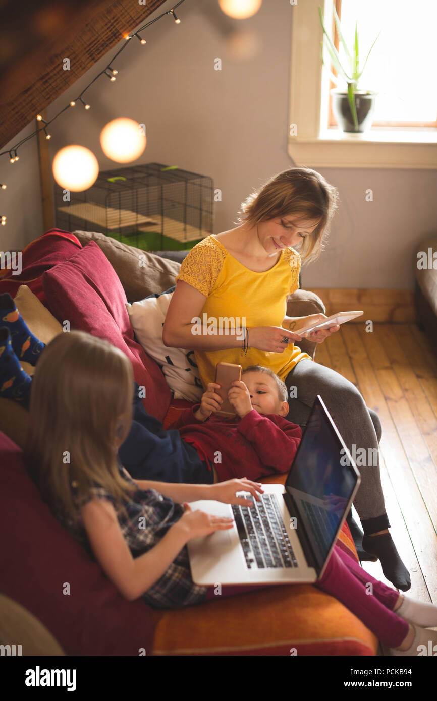 Family on sofa using multimedia devices Stock Photo