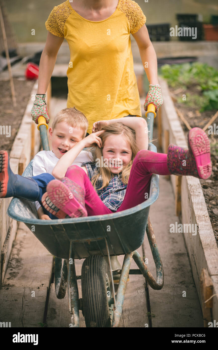 Mother having fun with kids in wheelbarrow Stock Photo - Alamy