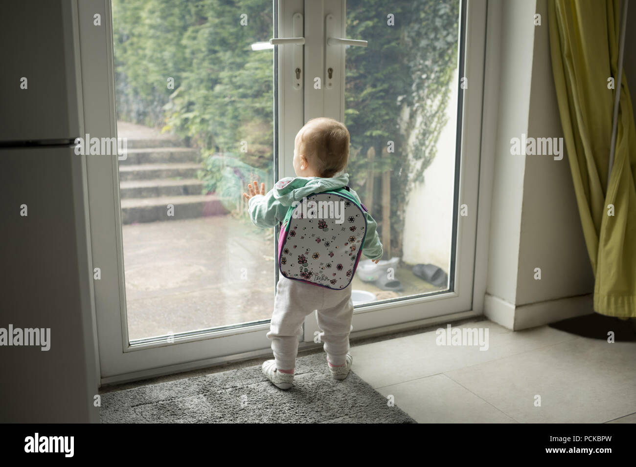 Baby Girl With Schoolbag Looking Through Door Stock Photo