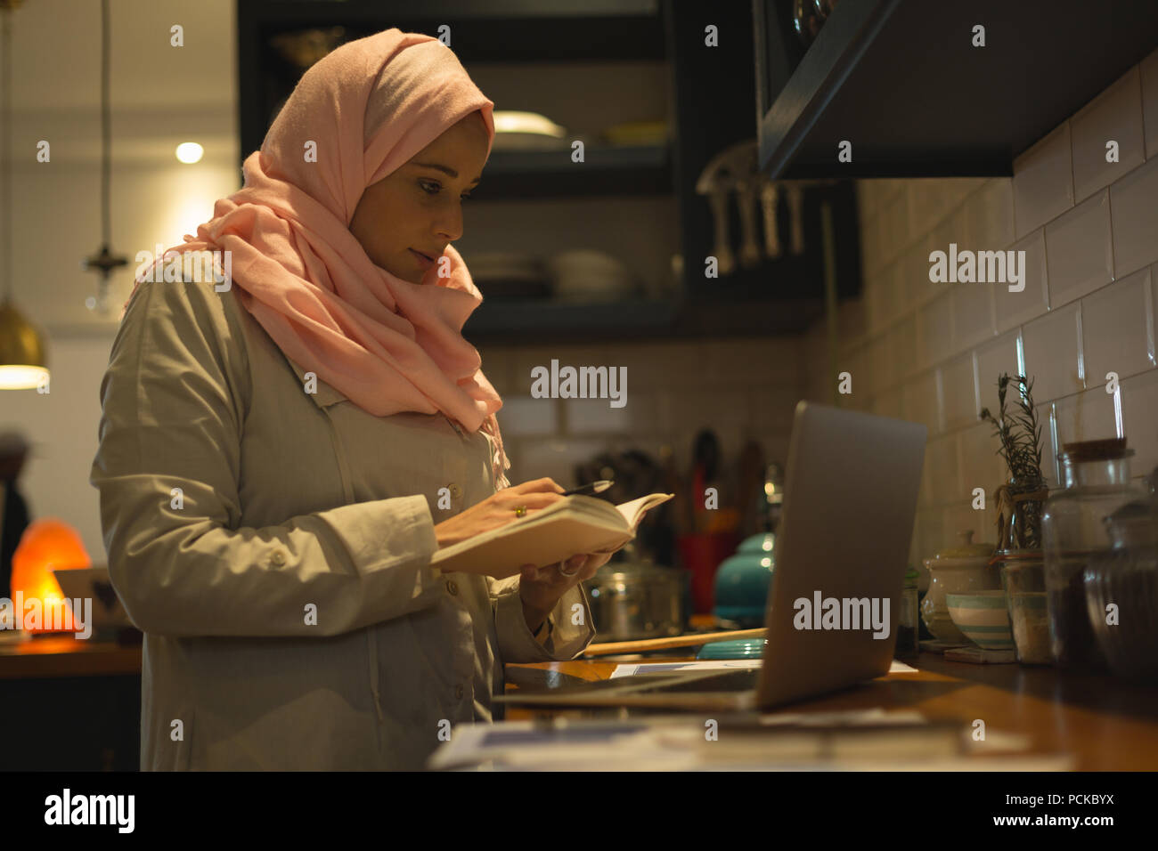 Muslim woman writing down the recipe from laptop Stock Photo
