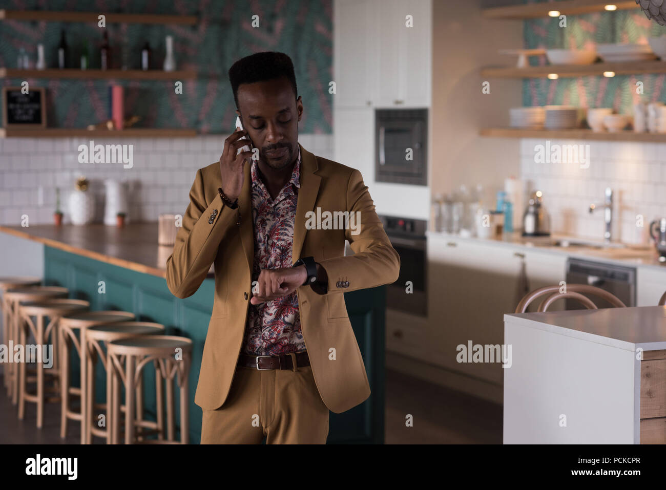 Businessman looking at smart watch while talking on mobile phone Stock Photo