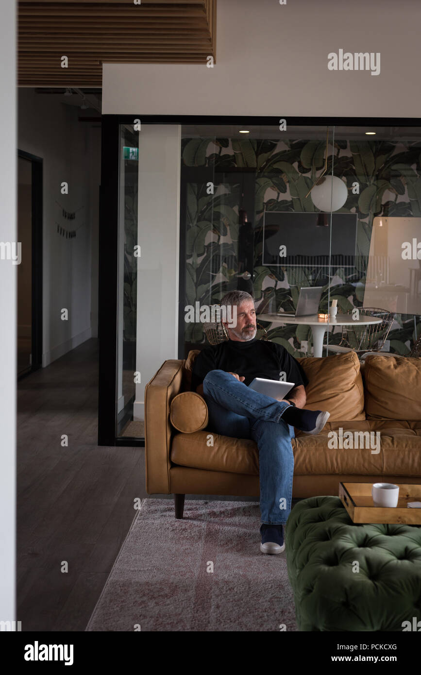 Thoughtful businessman using digital tablet on sofa Stock Photo