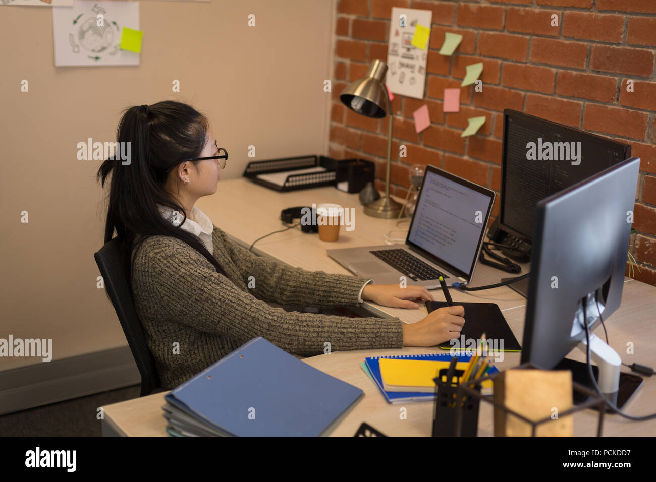 Female graphic designer using graphics tablet at desk Stock Photo