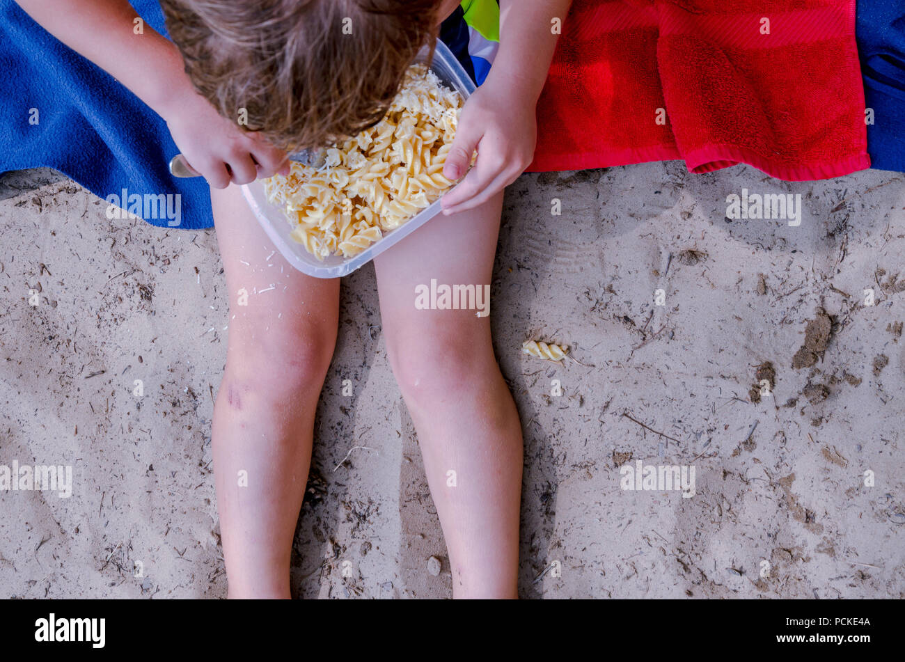 Children eating pasta on beach. Nice landscape of child playing