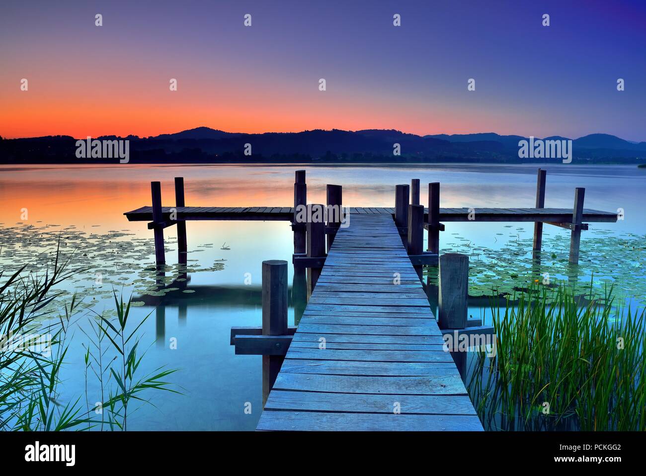 Wooden pier during dawn at Pfäffikersee, Pfäffikon, Canton of Zurich, Switzerland Stock Photo