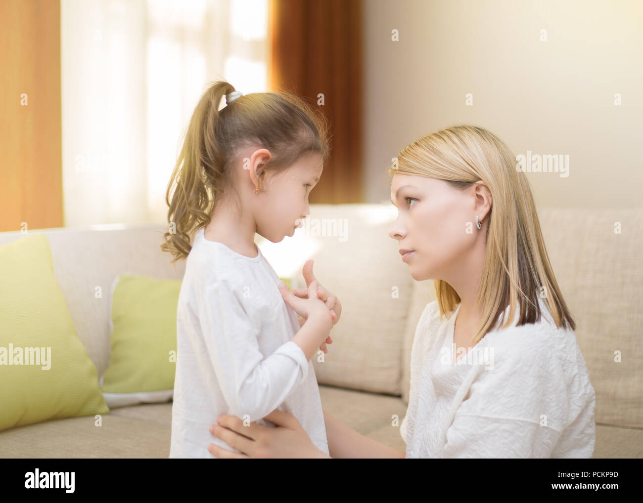 Beautiful mother is comforting her sad little daughter at home.  Stock Photo