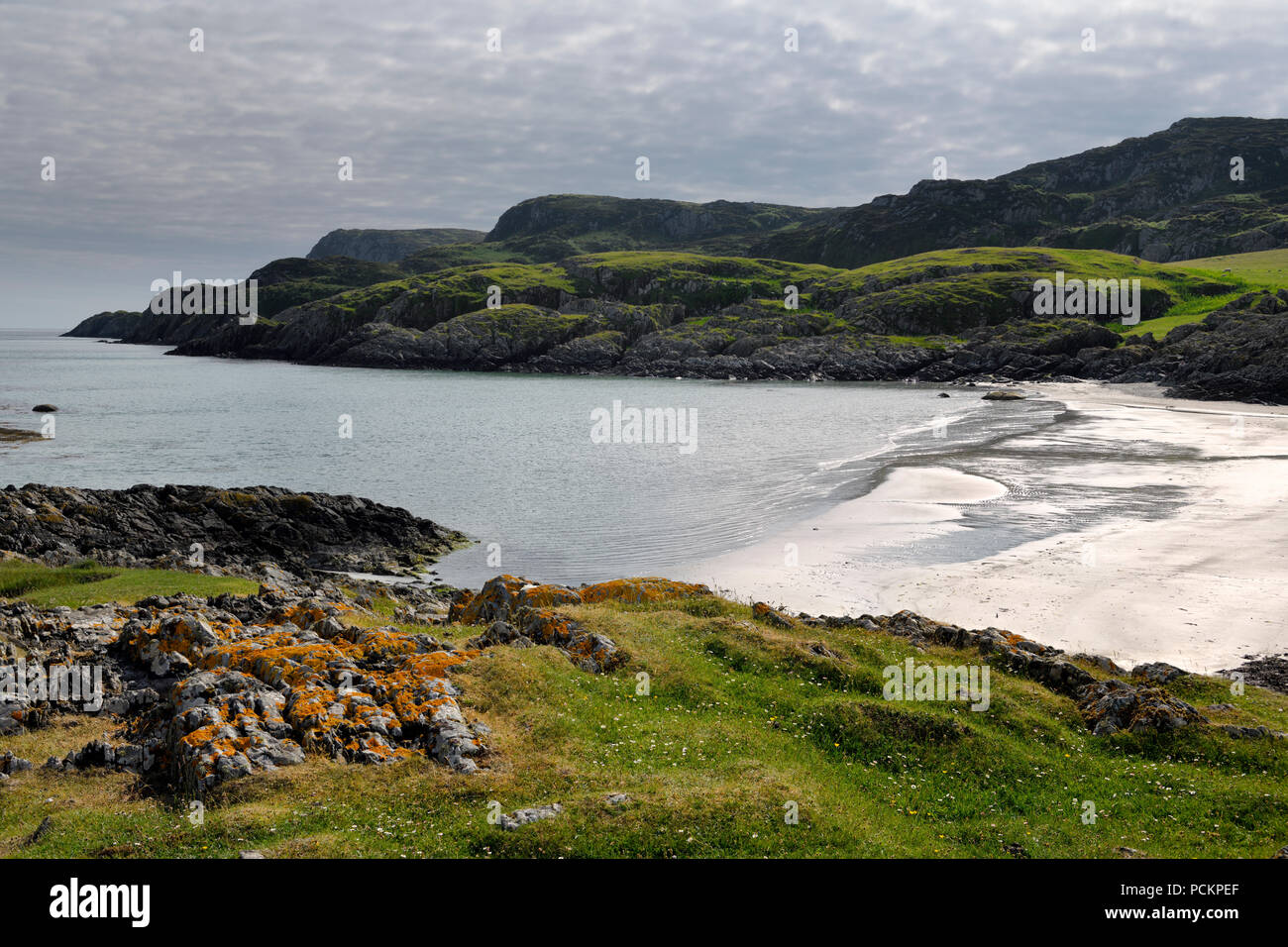Lichen covered rocks at Sandeels Bay above sandy beach on Isle of Iona Inner Hebrides Scotland UK Stock Photo
