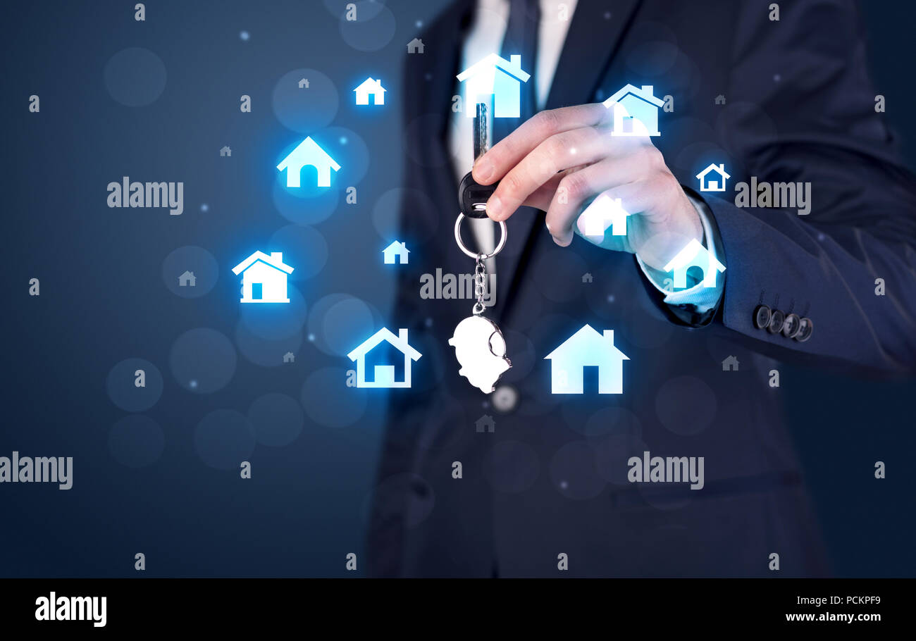 Businessman in suit holding keys with house graphics around and dark ...