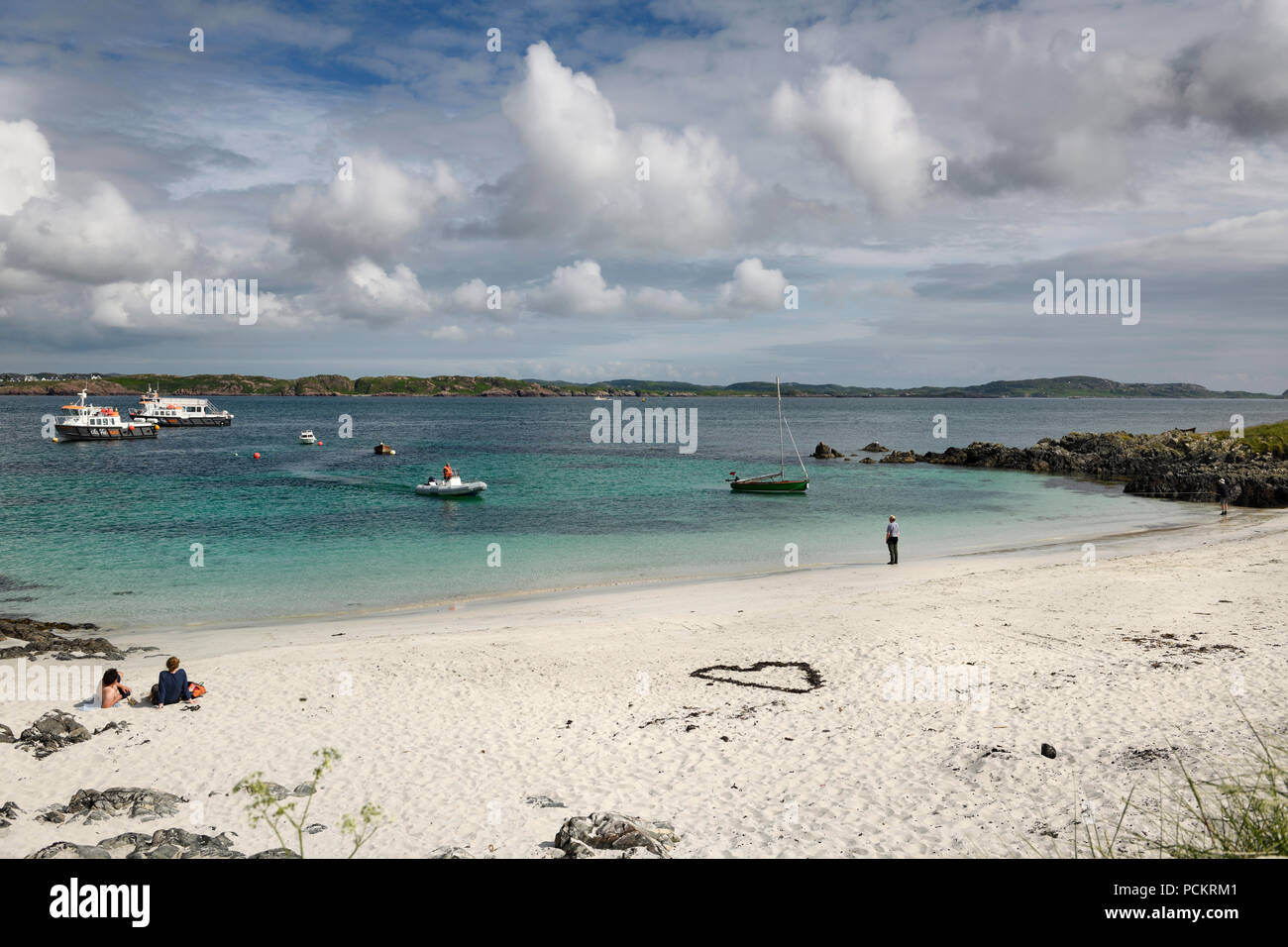 White sand beach of Martyr's Bay on Isle of Iona looking at Isle of Mull and boats in Sound of Iona Inner Hebrides Scotland UK Stock Photo