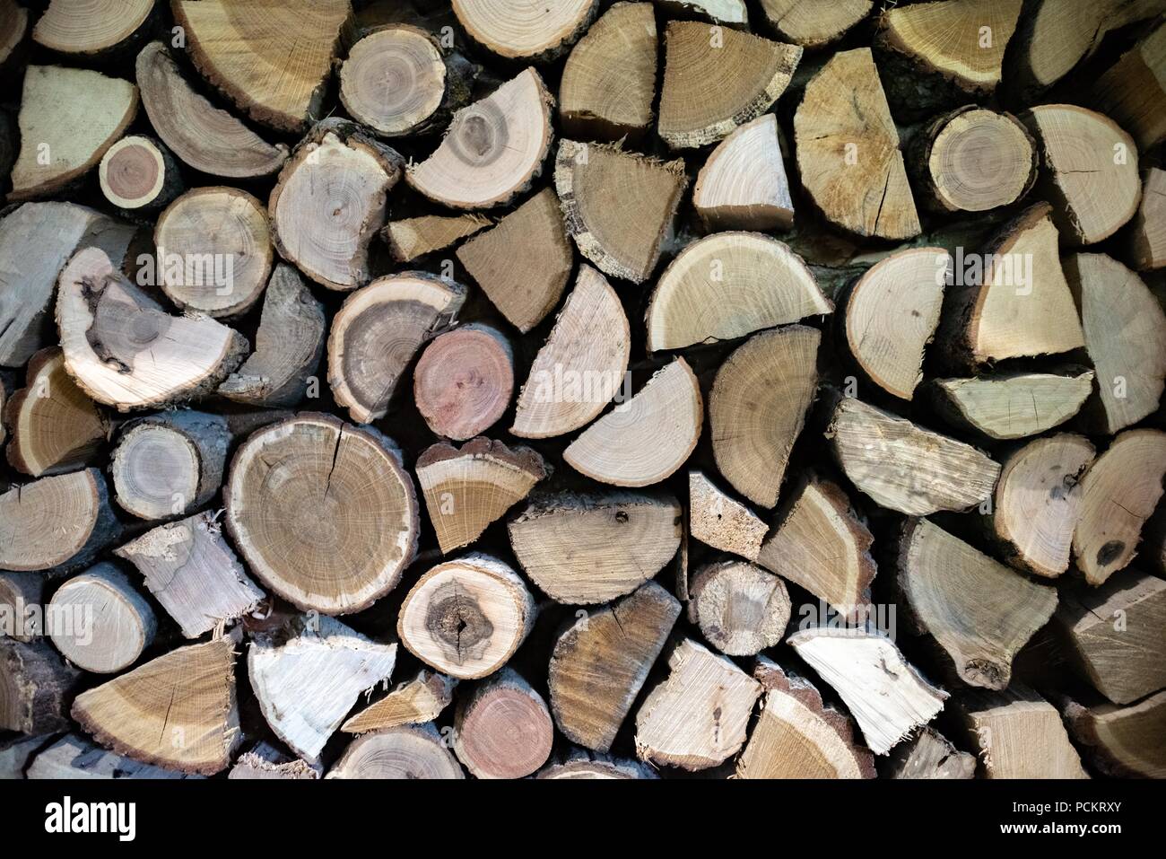 Natural wooden logs cut and stacked in pile, felled by the logging timber industry, Abstract photo of a pile of natural wooden logs background Stock Photo