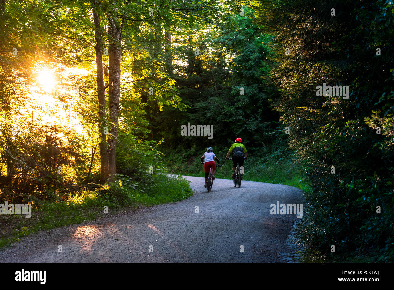 Two cyclists ride along a path in the evening light Stock Photo