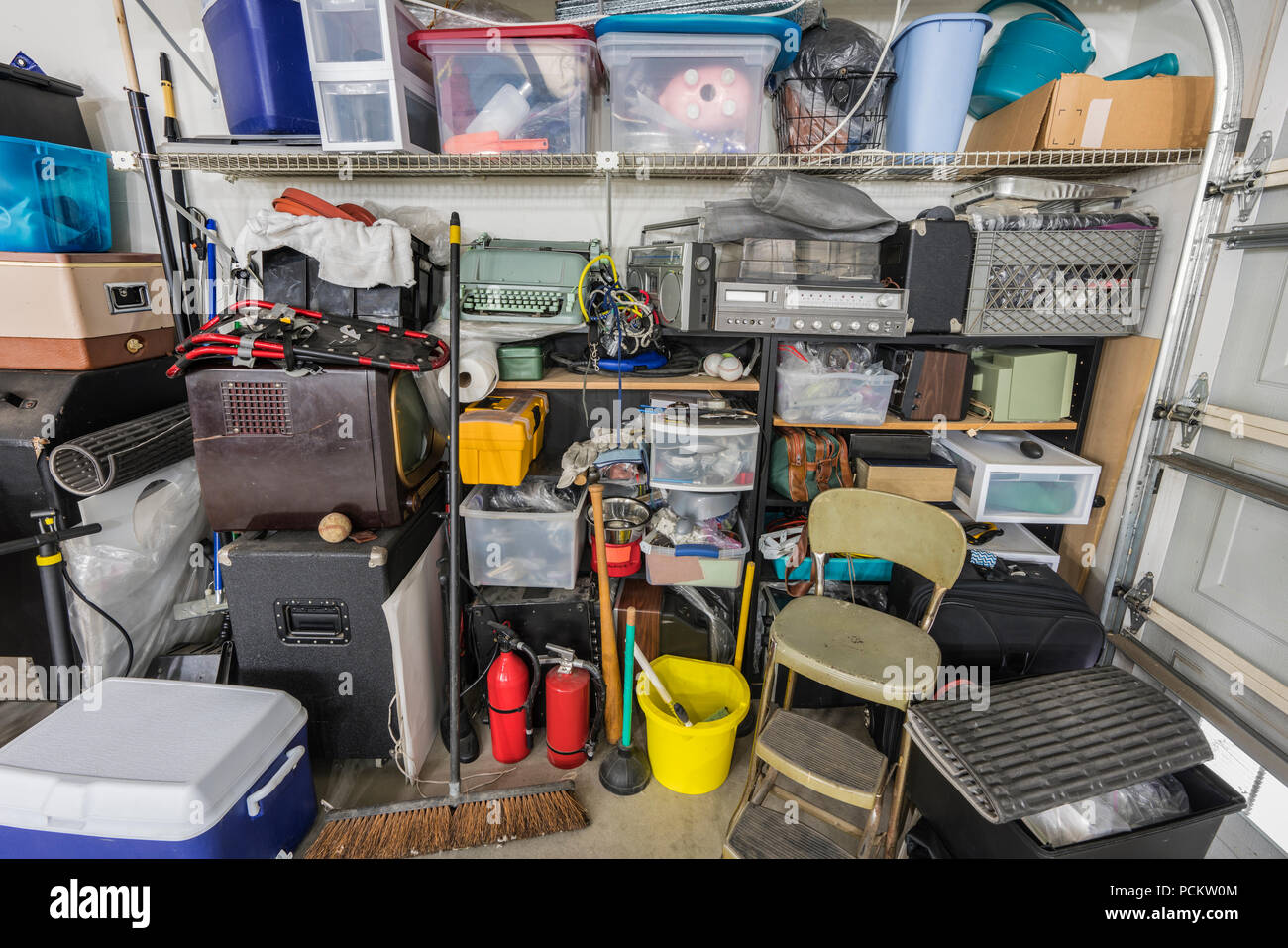 Messy cluttered junk filled suburban garage shelves with vintage electronics, housewares and sports equipment. Stock Photo