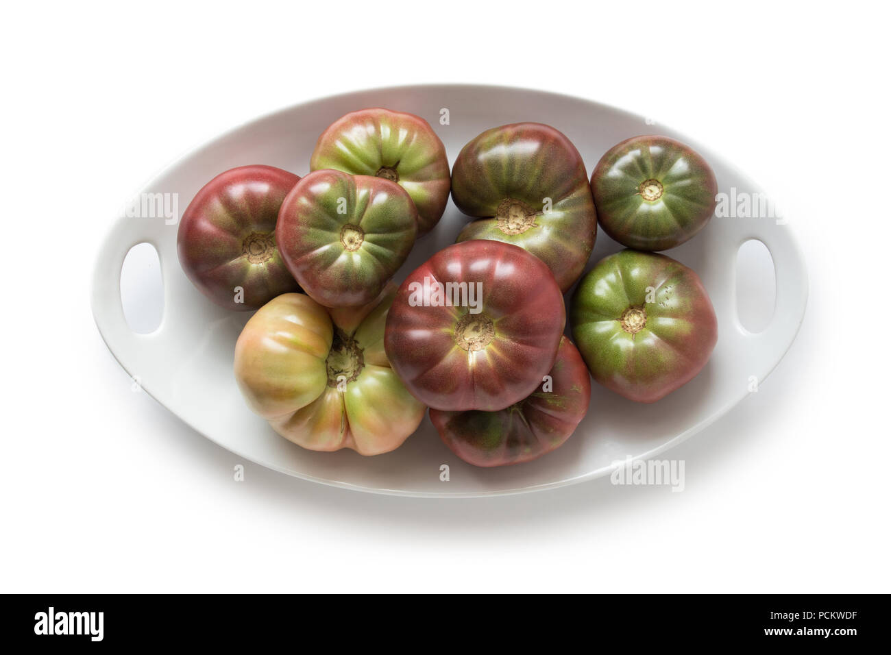 Organic heirloom Brandywine tomatoes on a plate, isolated on white, top