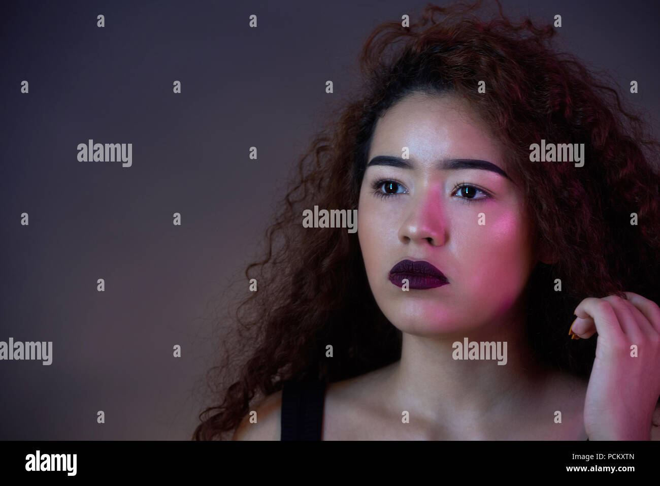 Colorful portrait of latina girl with curly hair on dark studio background Stock Photo
